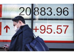 A man walks past an electronic stock board showing Japan's Nikkei 225 index at a securities firm in Tokyo Monday, Feb. 4, 2019. Asian markets were mixed Monday as traders questioned an imminent meeting between American and Chinese officials to work on disagreements ranging from technology development to trade.