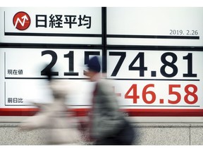 People walk past an electronic stock board showing Japan's Nikkei 225 index at a securities firm in Tokyo Tuesday, Feb. 26, 2019. Most Asian share benchmarks are lower as a rally spurred by the Trump administration's decision to hold off on increasing tariffs on imported Chinese goods fades.