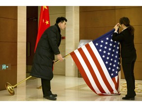 Chinese staffers adjust a U.S. flag before the opening session of trade negotiations between U.S. and Chinese trade representatives at the Diaoyutai State Guesthouse in Beijing, Thursday, Feb. 14, 2019.