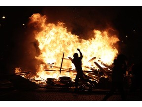FILE - In this Nov. 24, 2018, file photo, a demonstrator throws debris at a burning barricade while protesting with others against the rising of the fuel taxes on the famed Champs Elysees avenue, in Paris. The offer by Italy's 5-Star Movement to share its web platform with France's "yellow vests" could be harbinger of what's to come in the upcoming European Parliament elections.