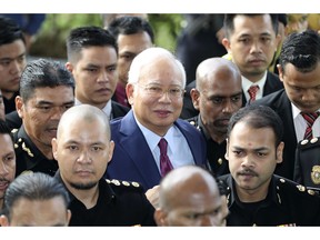 FILE - In this July 4, 2018, file photo, former Malaysian Prime Minister Najib Razak, center, arrives at a court house in Kuala Lumpur, Malaysia. Najib is hardly lying low ahead of his corruption trial set to begin Tuesday, Feb. 12, 2019, on charges related to the multibillion-dollar looting of the 1MDB state investment fund. He's crooned about slander in an R&B video and vilified the current government on social media to counter portrayals of him as corrupt and out of touch. Najib denies wrongdoing and his lawyers are seeking delay.