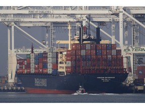 FILE - In this Nov. 14, 2018, file photo, a U.S. Coast Guard vessel patrols the Oakland estuary as the container ship Horizon Enterprise is unloaded in Oakland, Calif. The nation's business economists foresee a sharp slowdown in U.S. economic growth over the next two years, in sharp contrast to the Trump administration's predictions that growth will accelerate this year and next.