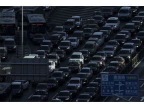FILE - In this Dec. 11, 2018, file photo, a beam of sunlight is cast on vehicles on a city ring-road clogged with heavy traffic during the morning rush hour in Beijing. The downturn in China's auto market worsened in January and February as sales plunged 17.5 percent from a year earlier.