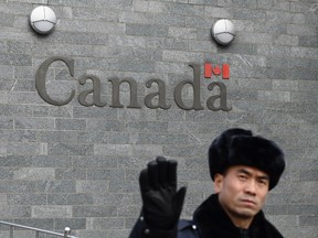 A guard attempts to block photos from being taken outside the Canadian embassy in Beijing on January 27, 2019.