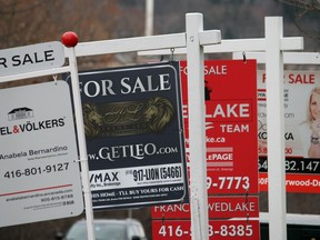 Real estate for sale signs are shown in Oakville, Ont. The Canadian Real Estate Association says home sales in February fell compared with a year ago as the average selling price also moved lower.