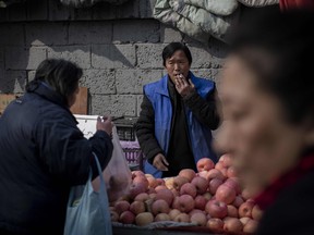 A woman buys apples at a market in Beijing on February 27, 2019. The Chinese economy is slowing down, which is stoking fears over the prospect of a worldwide recession.