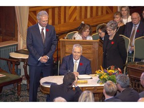 New Brunswick Progressive Conservative MLA Ernie Steeves, centre, is sworn in as Minister of Finance, and President of the Treasury Board at the New Brunswick Legislature in Fredericton on Friday, Nov. 9, 2018. New Brunswick's minority government will hand down its first budget Tuesday, saying it will offer the hard decisions needed to balance the province's finances.