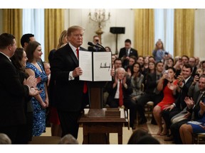 President Donald Trump shows off an executive order that he signed on "improving free inquiry, transparency, and accountability on campus" in the East Room of the White House, Thursday, March 21, 2019, in Washington.