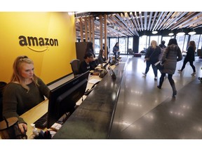 FILE - In this Nov. 13, 2018, file photo, employees walk through a lobby at Amazon's headquarters in Seattle.  Many of Amazon's Seattle-area employees will likely be exempt from new proposed labor protections after a push by the tech giant's lobbyists to raise the salary threshold at which the rules would kick in. The changes would partially prohibit so-called non-compete clauses, agreements widely used by tech companies and others to prohibit employees from going to work for competitors.