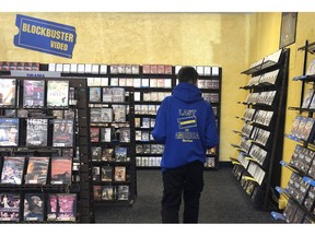 Employee Ryan Larrew reshelves movies that have been returned to the last Blockbuster store on the planet in Bend, Ore., in this Tuesday, March 12, 2019 photo. Larrew's sweatshirt advertises the store as the last one in America, but the store has ordered new sweatshirts and T-shirts saying it is the last Blockbuster on the planet. When a Blockbuster in Perth, Australia, shuts its doors for the last time on March 31, the store in Bend, Ore., will be the only one left on Earth, and most likely in the universe.