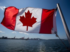 A Canadian flag flies from a Harbour Authority patrol boat as gantry cranes are seen at the Port of Vancouver in Vancouver, British Columbia, on July 11, 2017. MUST CREDIT: