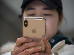 A woman uses an Apple iPhone at a shopping mall in Beijing on January 3, 2019.