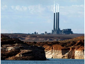 FILE - In this Sept. 4, 2011, file photo, smoke rises from the stacks of the main plant facility at the Navajo Generating Station, as seen from Lake Powell in Page, Ariz. The Navajo Nation company has ended its pursuit of a coal-fired power plant on the reservation and the mine that feeds it. The decision Friday, March 22, 2019 means the Navajo Generating Station and the Kayenta Mine will close this year, ending decades of operation in northeastern Arizona. The bid by the Navajo Transitional Energy Company had been considered a long-shot.