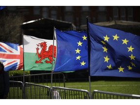 A Welsh flag, second left, placed by protestors who support Britain remaining in the European Union is blown in the wind next to a Union flag, at left, and two European flags near the Houses of Parliament in London, Tuesday, March 5, 2019. The National Assembly for Wales and the Scottish Parliament are both due to vote later Tuesday on motions declaring opposition to British Prime Minister Theresa May's Brexit deal and declare their opposition a no-deal Brexit.