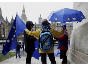 Remain supporters shelter from the wind and rain across the street from parliament in London,  Thursday Feb. 28, 2019.  British Prime Minister Theresa May has offered Parliament the chance to delay Britain's scheduled March 29 departure if lawmakers fail to approve her divorce agreement with the bloc.