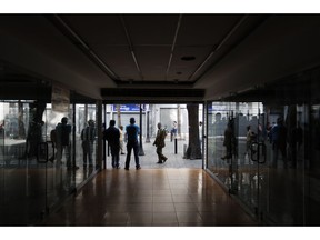 People walk past darken store fronts in Caracas, Venezuela, Friday, March 8, 2019. Much of Venezuela was still without electricity Friday amid the country's worst-ever power outage, raising tensions in a country already on edge from ongoing political turmoil. President Nicolas Maduro ordered schools and all government entities closed and told businesses not to open to facilitate work crews trying to restore power.