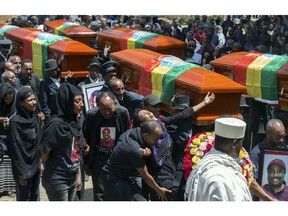 Relatives grieve next to empty caskets draped with the national flag at a mass funeral at the Holy Trinity Cathedral in Addis Ababa, Ethiopia Sunday, March 17, 2019. Thousands of Ethiopians have turned out to a mass funeral ceremony in the capital one week after the Ethiopian Airlines plane crash. Officials have begun delivering bags of earth to family members of the 157 victims of the crash instead of the remains of their loved ones because the identification process is going to take such a long time.