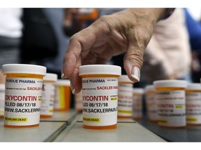 FILE - In this Aug. 17, 2018 file photo, family and friends who have lost loved ones to OxyContin and opioid overdoses leave pill bottles in protest outside the headquarters of Purdue Pharma, which is owned by the Sackler family, in Stamford, Conn. The company that has made billions selling the prescription painkiller OxyContin says it is considering bankruptcy as one of several possible legal options, in an email to The Associated Press.