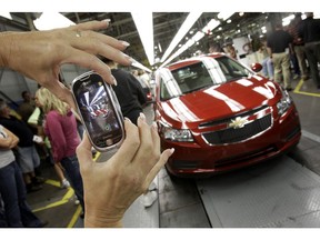 FILE - In this Sept. 8, 2010, file photo, an auto worker takes a picture of the first Chevrolet Cruze compact sedan to come off the assembly line at a ceremony inside the GM factory in Lordstown, Ohio. GM employees in Lordstown and other factories in Michigan and Maryland that are targeted to close within a year say moving will force them to leave behind relatives, even their children, in some cases.