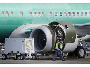 FILE- In this March 13, 2019, file photo a worker walks past an engine on a Boeing 737 MAX 8 airplane being built for American Airlines at Boeing Co.'s Renton assembly plant in Renton, Wash. U.S. prosecutors are looking into the development of Boeing's 737 Max jets, a person briefed on the matter revealed Monday, the same day French aviation investigators concluded there were "clear similarities" in the crash of an Ethiopian Airlines Max 8 last week and a Lion Air jet in October.