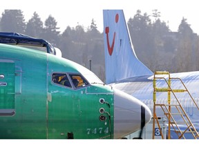 FILE- In this March 13, 2019, file photo people work in the flight deck of a Boeing 737 MAX 8 airplane being built for TUI Group parked next to another MAX 8 also designated for TUI at Boeing Co.'s Renton Assembly Plant in Renton, Wash. U.S. prosecutors are looking into the development of Boeing's 737 Max jets, a person briefed on the matter revealed Monday, the same day French aviation investigators concluded there were "clear similarities" in the crash of an Ethiopian Airlines Max 8 last week and a Lion Air jet in October.