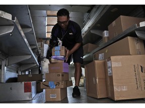 FILE- In this July 17, 2018, file photo, a FedEx employee delivers packages in Miami. FedEx reports financial results on Tuesday, March 19, 2019.