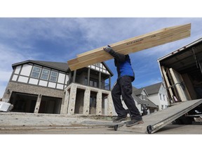 In this Feb. 20, 2019, photo a worker carries interior doors to install in a just completed new home in north Dallas. On Wednesday, March 13, the Commerce Department reports on U.S. construction spending in January.