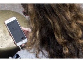 FILE- In this Aug. 1, 2018, file photo, a woman uses a ride-hailing app while waiting for a ride outside Grand Central Terminal in New York. Ride-hailing giants Uber and Lyft have redefined what we expect from transportation. But it's unclear whether the companies can turn their popularity into profits.