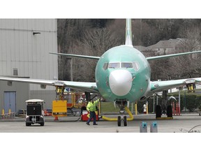 FILE- In this March 11, 2019, file photo a worker stands near a Boeing 737 MAX 8 airplane parked at Boeing Co.'s Renton Assembly Plant in Renton, Wash. Boeing soared early in 2019 and lifted the Dow Jones Industrial Average with it. Now concerns about the safety of the newest version of its flagship airplane have halted the momentum.