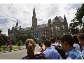 FILE - In this July 10, 2013, file photo, prospective students tour Georgetown University's campus in Washington. Federal authorities have charged college coaches and others in a sweeping admissions bribery case in federal court. The racketeering conspiracy charges were unsealed Tuesday, March 12, 2019, against the coaches at schools including Georgetown, Wake Forest University and the University of Southern California. Authorities say the coaches accepted bribes in exchange for admitting students as athletes, regardless of their ability.