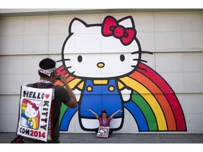 FILE - In this Oct. 30, 2014, file photo, Keith Nunez, left, takes pictures of his wife, Carolina, at the first-ever Hello Kitty fan convention, Hello Kitty Con, at the Geffen Contemporary at MOCA in Los Angeles. Hello Kitty might not have a mouth but she's got a movie deal. Warner Bros.'s New Line Cinema announced Tuesday, March 5, 2019, that it has acquired film rights to Hello Kitty from the Japanese corporation Sanrio.