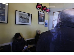 People are seen through a glass window as they wait inside a fiscal consultancy office to apply for the minimum income, in Rome, Wednesday, March 6, 2019. On Wednesday Italians are began queueing at post offices and fiscal consultancy offices on the first day of application of the request for the 'low income salary', a public subsidy for people whose monthly income is below 780,00 euros. The low income salary (reddito di cittadinanza) was among the main pledges of the Five Stars Movement during the past electoral campaign.