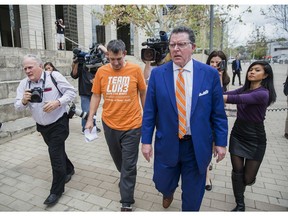 Texas men's tennis coach Michael Center, center left, walks with Defense lawyer Dan Cogdell, center right, away from the United States Federal Courthouse in Austin, Texas, Tuesday, March 12, 2019. Center is among a few people in the state charged in a scheme that involved wealthy parents bribing college coaches and others to gain admissions for their children at top schools, federal prosecutors said Tuesday. (Ricardo B. Brazziell