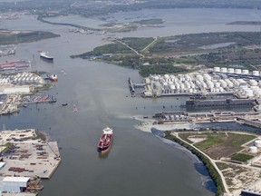 In a Wednesday, March 20, 2019 photo, maritime traffic moves through the Houston Ship Chanel past the site of now-extinguished petrochemical tank fire at Intercontinental Terminals Company in Deer Park, Texas. Air quality and water pollution from the fire's runoff, seen on the right, into the ship channel are some of the concerns in the aftermath of the blaze.