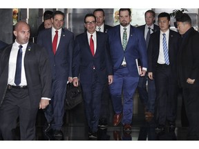 U.S. Treasury Secretary Steven Mnuchin, third from left, is escorted by bodyguards and a delegation leaves a hotel in Beijing, Friday, March 29, 2019. U.S. trade negotiators lead by Mnuchin and Trade Representative Robert Lighthizer arrived in Beijing to start a new round of talks aimed at ending a tariff war over China's technology ambitions as officials hint they might be making progress.