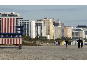 In this photo taken on Jan. 21, 2019, people walk past a lifeguard booth painted in the colors of an American flag on a beach in Miami Beach, Fla. The Miami area is popular among Russians not only for its tropical weather but also because of the large Russian-speaking population. Sunny Isles Beach, a city just north of Miami, is even nicknamed "Little Moscow".