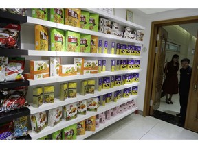 In this March 13, 2019, photo, employees peek through a door into a showroom at a food factory in Pyongyang, North Korea. North Korean factories are filling city store shelves with ever better and fancier snack foods and sugary drinks, while government officials and international aid organizations warn the nation could be on the verge of a major food crisis.