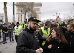 Eric Drouet, center, one of yellow vests leaders chats with supporters in Paris, France, Saturday, March 2, 2019. French yellow vests are protesting for a 16th straight weekend in Paris and other cities to show they are still mobilized against the government's economic policies they see as favoring the rich.