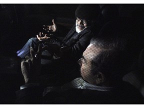 In this March 6, 2019, photo, former Nissan chairman Carlos Ghosn, foreground, and his lawyer Takashi Takano, rear, chat in a car after Ghosn was bailed out from Tokyo's Detention Center in Tokyo. The mystery of Carlos Ghosn's strange attire when he was released from Japanese detention has been solved, with his lawyer Takano saying Friday, March 8, that it was an effort to protect the former chairman of Nissan from intense media attention.