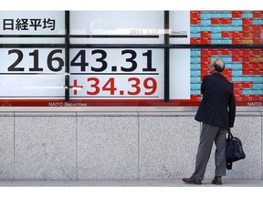A man looks at an electronic stock board showing Japan's Nikkei 225 index at a securities firm in Tokyo Friday, March 22, 2019. Asian markets were mostly lower on Friday as investors mulled over the possibility of a trade deal between the U.S. and China in the near future, ahead of the continuation of talks in Beijing next week.