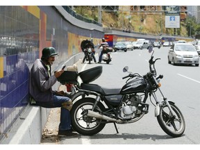 Enrique Quiroga, a moto-taxi driver, speaks with his son in Spain as he and other motorists stop on the road near a working cell phone tower during rolling blackouts in Caracas, Venezuela, Monday, March 11, 2019. Some say the cell phone tower is one of the few in regular operation, transforming the spot into one of the city's most popular destinations.