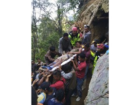 In this undated photo released by Indonesian Search And Rescue Agency (BASARNAS) rescuers evacuate a survivor from inside of a collapsed gold mine in Bolaang Mongondow, North Sulawesi, Indonesia. The collapse of an unlicensed gold mine in Indonesia's North Sulawesi province has buried dozens of people, a disaster official said Wednesday, Feb. 27, 2019, as emergency personnel used their bare hands and farm tools in a desperate attempt to reach victims calling for help from beneath the rubble.