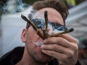 A reveller smokes three joints at once while attending the 4/20 annual marijuana celebration, in Vancouver, B.C., on Friday April 20, 2018.