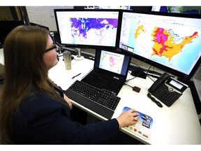 FILE - In this March 21, 2019 file photo, Whitney Flynn, a physical scientist at the National Water Center in Tuscaloosa, Ala., works on computer screens showing flood predictions and other information. An arsenal of new technology is being put to the test fighting floods this year as rivers inundate towns and farm fields across the central United States. Drones, supercomputers and sonar that scans deep under water are helping to maintain flood control projects, and predicting just where rivers will roar out of their banks.