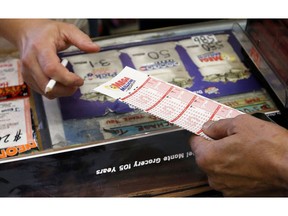 FILE - In this Tuesday, Dec. 17, 2013 file photo, Keith Ganatra, right, owner of the Del Monte Market, takes the numbers form picked by a customer, as he sells Mega Millions lottery tickets at a brisk pace in Laveen, Ariz. A growing number of states are moving to allow winners of big lottery jackpots to stay anonymous, and Arizona could join the list under a proposal headed to Republican Gov. Doug Ducey.