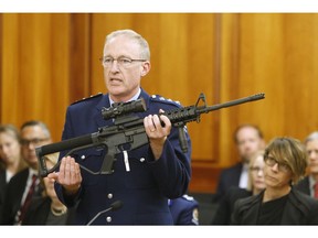 FILE - In this April 2, 2019, file photo, Police acting superintendent Mike McIlraith shows New Zealand lawmakers in Wellington, New Zealand, an AR-15 style rifle similar to one of the weapons a gunman used to slaughter 50 people at two mosques. New Zealand's new gun laws have been signed into law and now ban military-style weapons, just one day after the nation's parliament overwhelmingly approved legislation to outlaw them less than a month after a man used such guns to kill 50 worshippers at two mosques.
