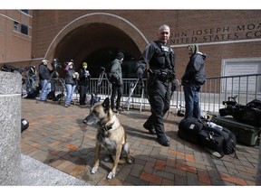 A Department of Homeland Security officer patrols with his K-9 outside federal court in Boston on Wednesday, April 3, 2019, where actress Felicity Huffman, actress Lori Loughlin and her husband, clothing designer Mossimo Giannulli are scheduled to attend an afternoon hearing in a nationwide college admissions bribery scandal.