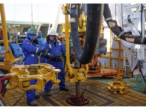 Trainee Kyle Robinson, left, talks with instructor Clint Dyck train to lay down drill pipe on a rig floor at Precision Drilling in Nisku, Alta., on Friday, January 20, 2016. Precision Drilling Corp. says it earned a profit in its latest quarter compared with a loss a year ago as its revenue improved eight per cent.