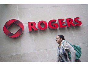 A pedestrian walks past the Rogers Building in Toronto on April 22, 2014. The federal government will get nearly $3.47 billion from its auction of 600 megahertz spectrum licences, which will be used by Canada's wireless communications networks. Rogers Communications will spend $1.72 billion to acquire 52 licences, making it by far the biggest spender.