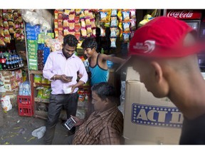 In this Monday, April 8, 2019, photo, Ram Shankar Rai, center, watches election campaign advertisements on his mobile phone outside his shop in New Delhi, India. From manipulated pictures being picked up by mainstream news media, to misrepresented quotes sparking communal division, false news and hateful propaganda on digital platforms are at peak levels in the run-up to the Indian general elections.